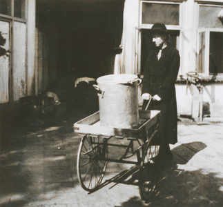 876771 Afbeelding van een handkar met een gamel met voedsel gekookt in de gaarkeuken, die ingericht is in klooster ...